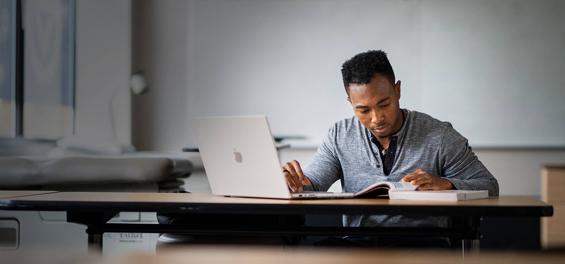 Student at desk with computer and textbook